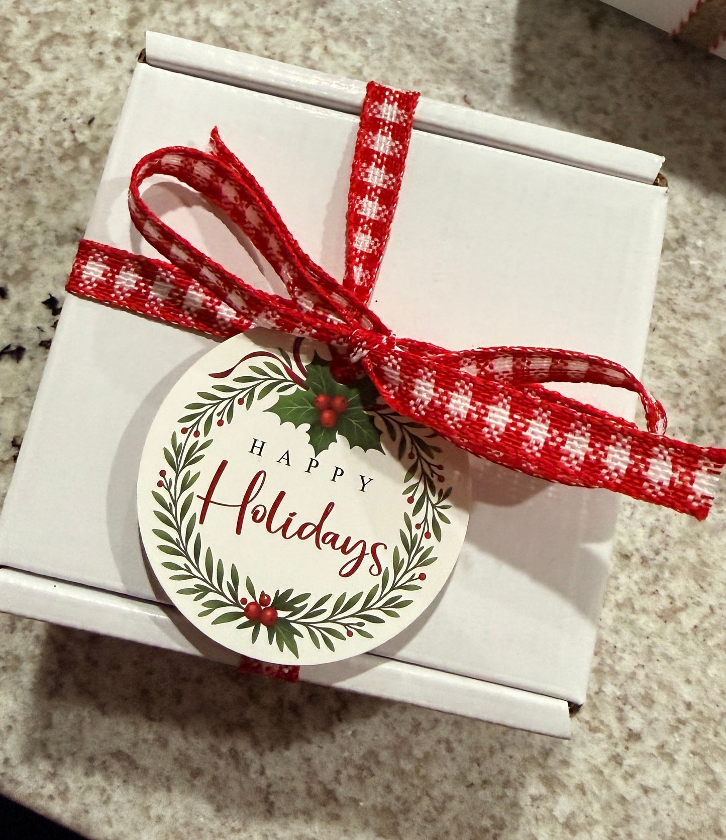 Gift box with a red ribbon and 'Happy Holidays' tag on a textured surface