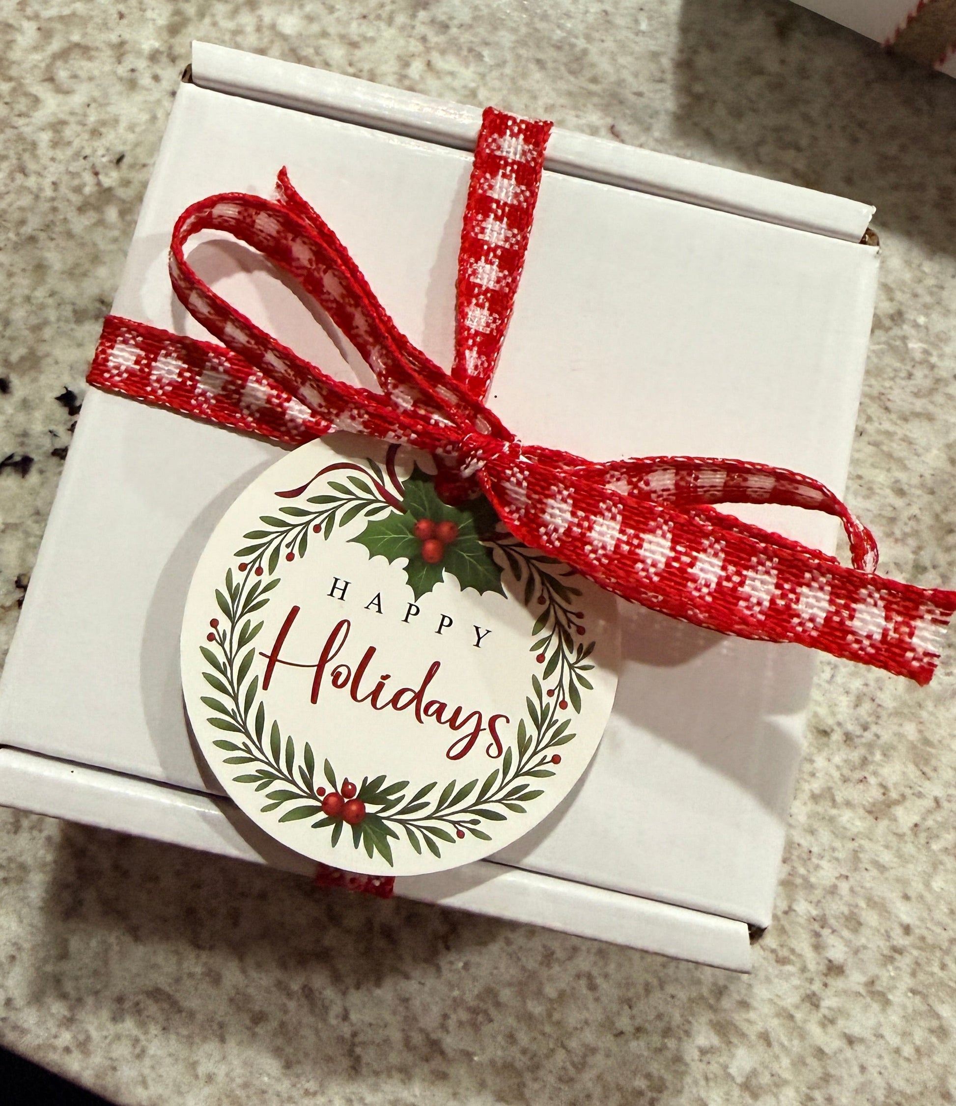 Gift box with a red ribbon and 'Happy Holidays' tag on a textured surface
