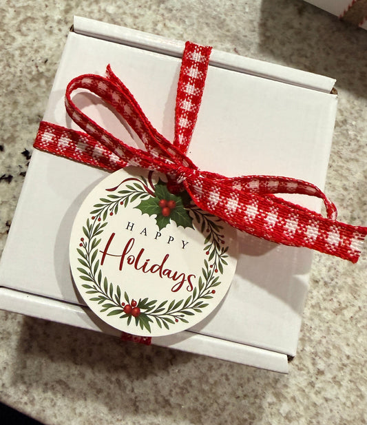 Gift box with a red ribbon and 'Happy Holidays' tag on a textured surface